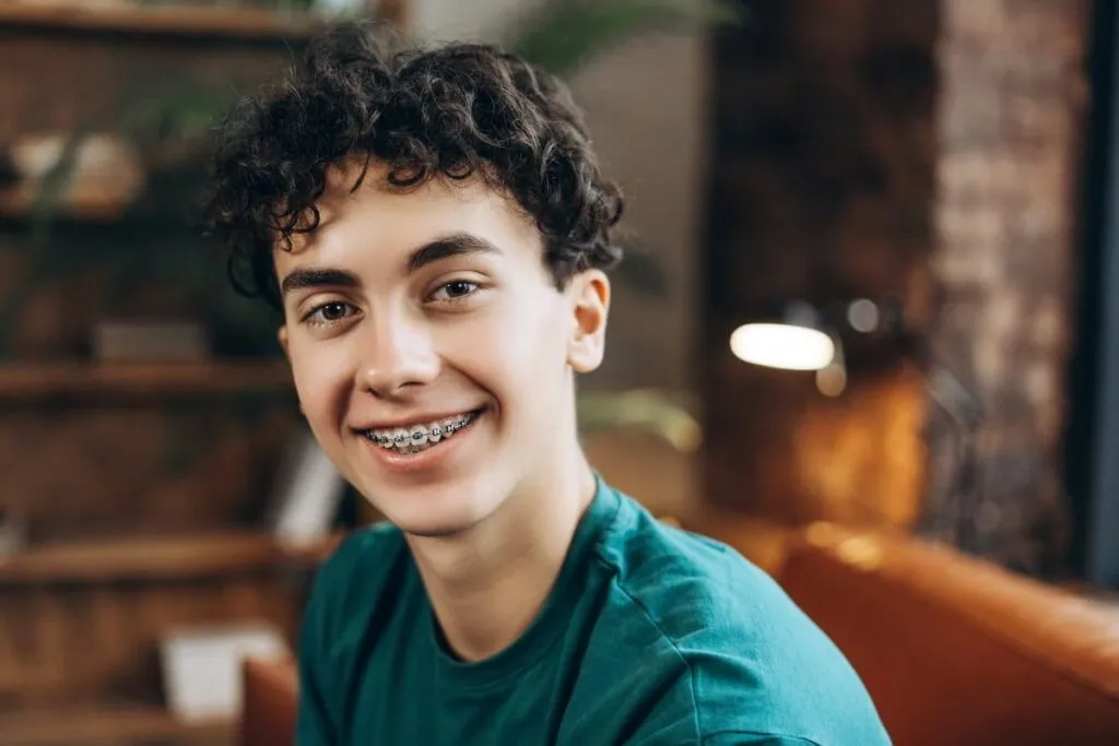 Close up of positive teenage boy with braces wearing t shirt posing at camera