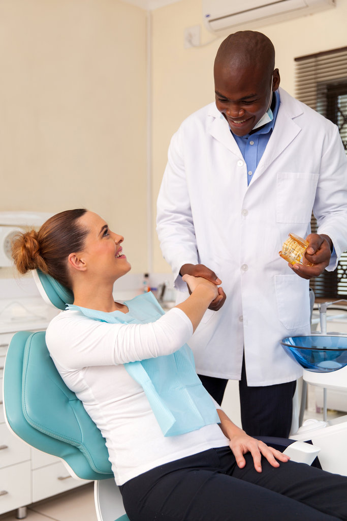 cheerful young woman shaking hands with dentist after teeth checkup